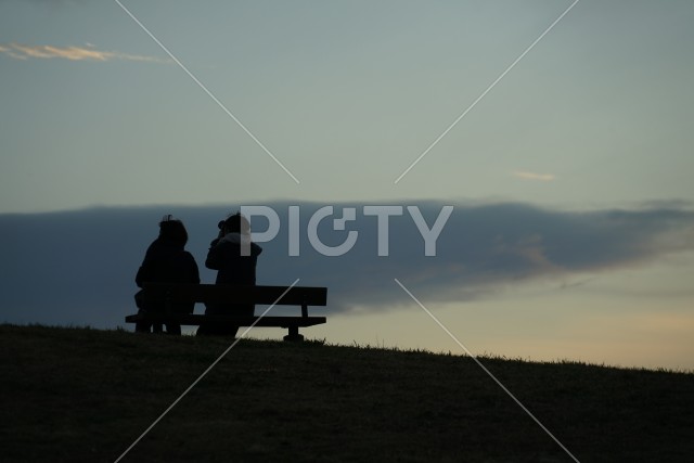 日没の丘のベンチに座る親子