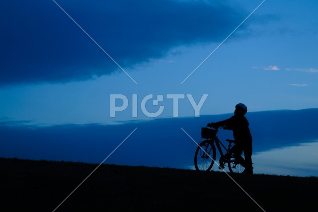 日没の丘で自転車に乗る少年