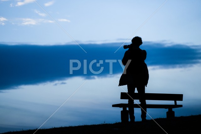 日没の丘に立つ男性のシルエット