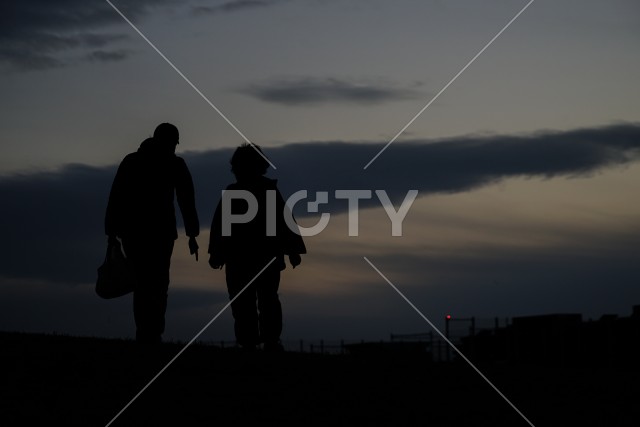 日没の丘に立つ親子のシルエット