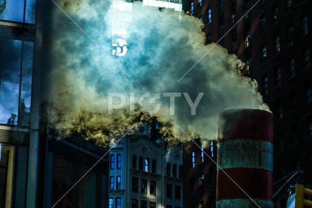 煙突から出る煙とニューヨークのビル街