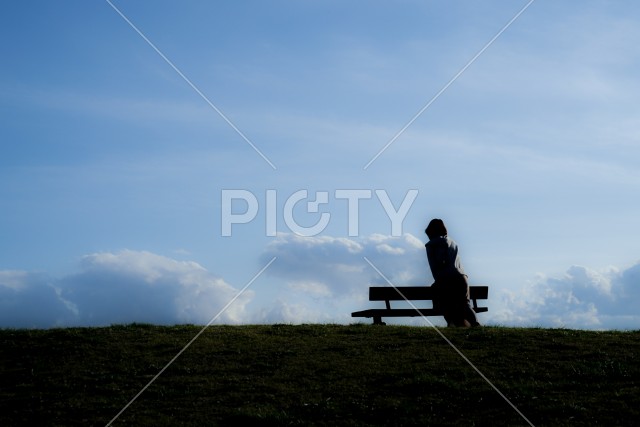 夕焼けの丘に座る女性のシルエット