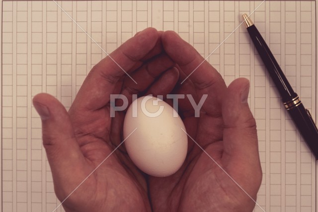 原稿用紙と卵を持つ手