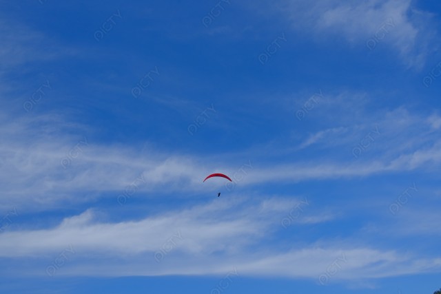 青空を飛ぶ赤いパラグライダー