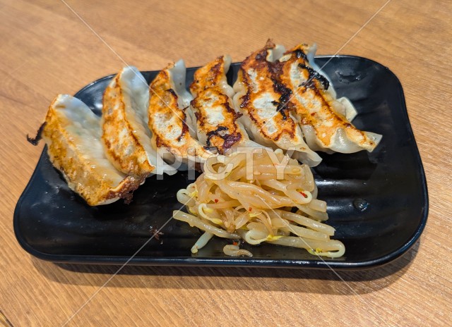 お皿に盛りつけられた焼き立ての餃子ともやしのナムル