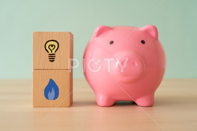 光熱費の節約イメージ｜電気とガスのマークが書かれた積み木と豚の貯金箱