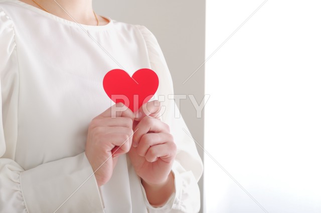 胸元でハートのオブジェを持つ女性