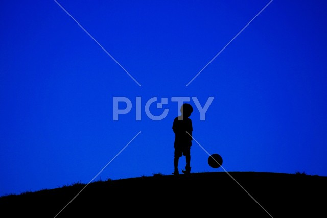 サッカーボールで遊ぶ少年（電線なし）