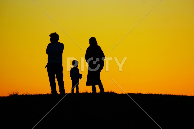 夕暮れの丘に立つ家族