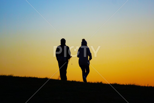 夕暮れの丘を歩く二人