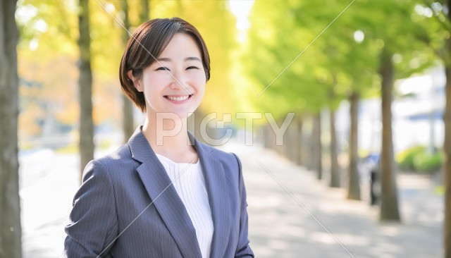 新緑の外で笑顔のスーツの女性