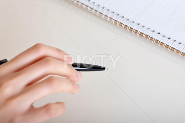 ペンを持つ手とリングノート