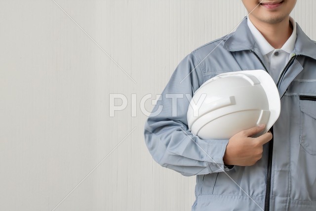 ヘルメットを持った作業着を着た男性