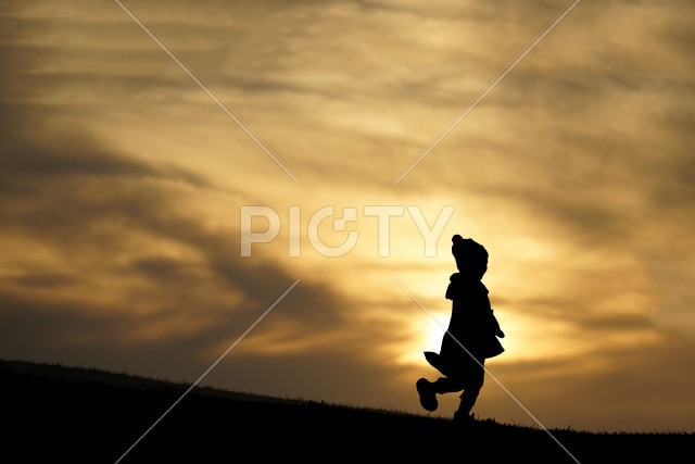 夕暮れの丘に立つ少女