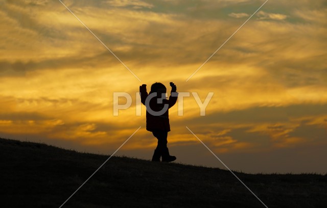 夕暮れの丘に立つ少年