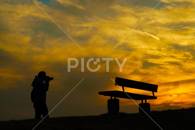 夕暮れの丘と写真を撮る男性